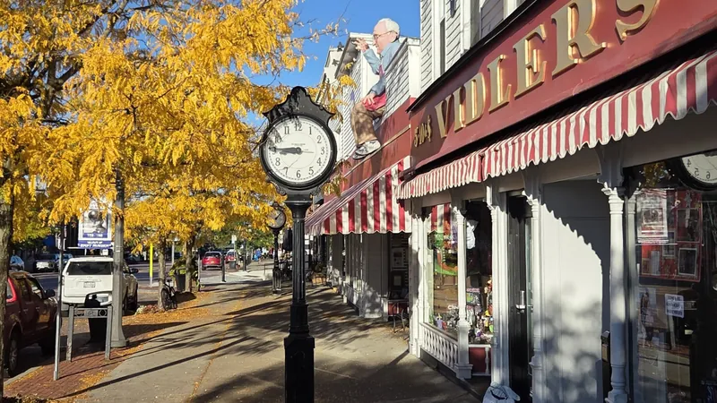 Main Street in East Aurora on a sunny fall day, with a street clock and the striped awnings of Vidler's 5 & 10