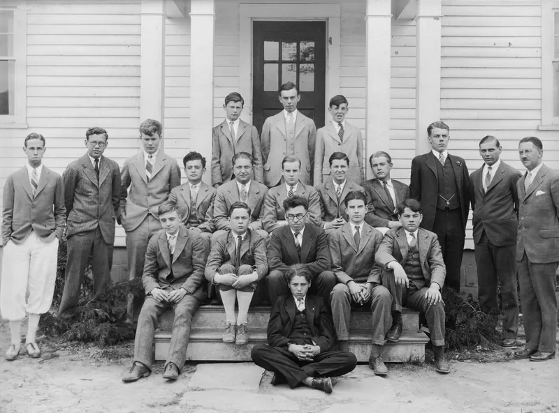 Black-and-white group photograph of Gow faculty and students in jackets and ties, gathered on the front steps of a white clapboard building in 1929