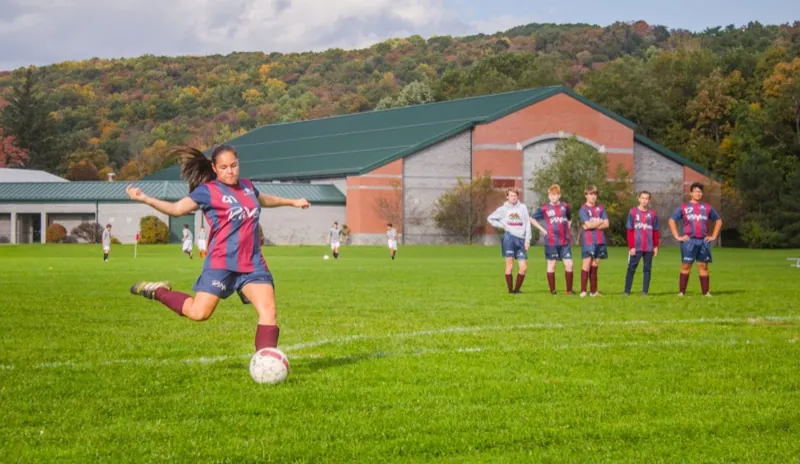 A student kicks a soccer ball on the field