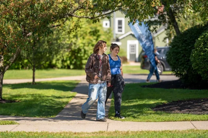 Two students walking across the campus lawn